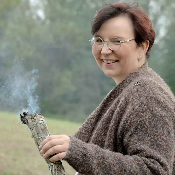 Nicole Dreis lacht in die Kamera, ein Räucherbündel in der Hand
