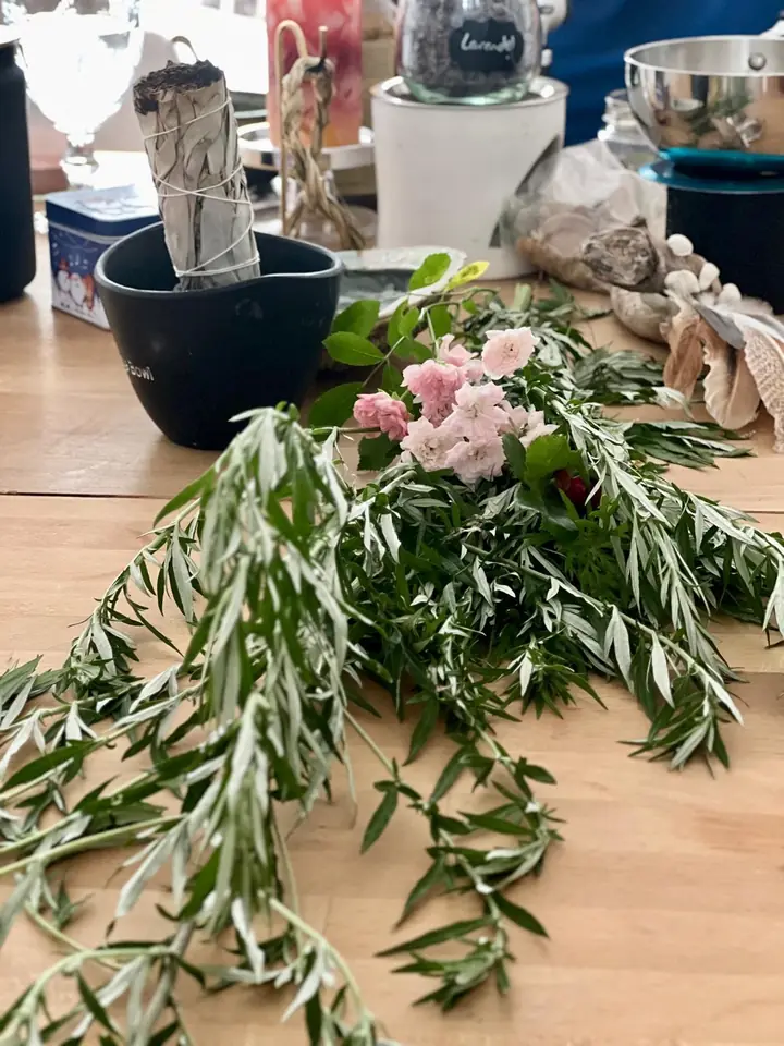Gedeckter Workshop-Tisch mit Kräutern, Blüten und Räucherbündel